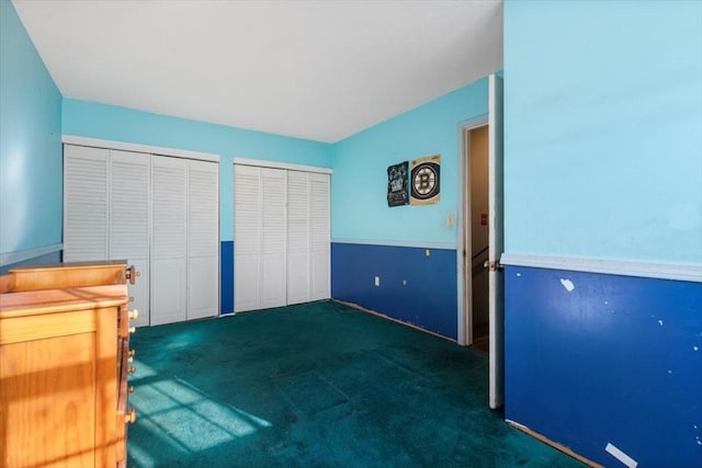 unfurnished bedroom featuring dark colored carpet and two closets