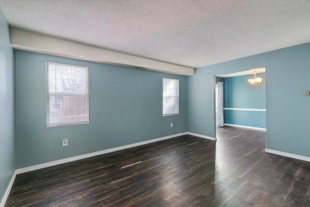 unfurnished room featuring a notable chandelier, a healthy amount of sunlight, and dark hardwood / wood-style flooring