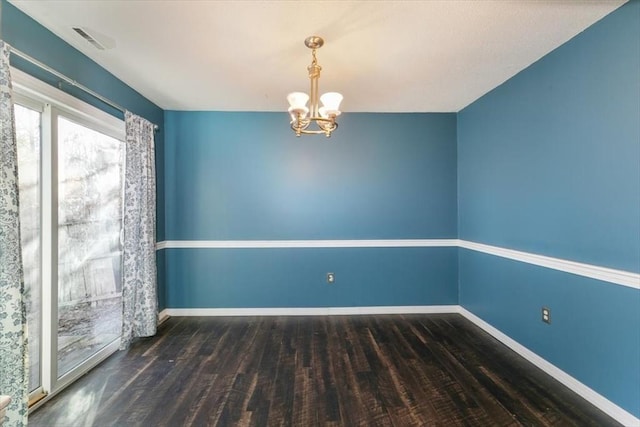 empty room with dark hardwood / wood-style floors and an inviting chandelier