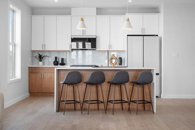 kitchen featuring a breakfast bar, hanging light fixtures, backsplash, and a center island