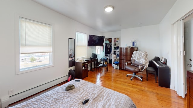 bedroom with multiple windows, baseboard heating, and light hardwood / wood-style flooring