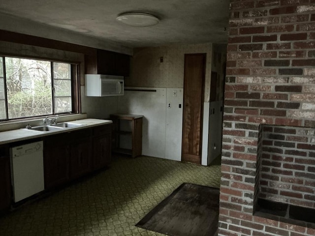 kitchen featuring white appliances, light countertops, and a sink