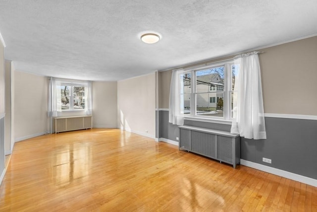 unfurnished room featuring radiator, a textured ceiling, and light wood-type flooring