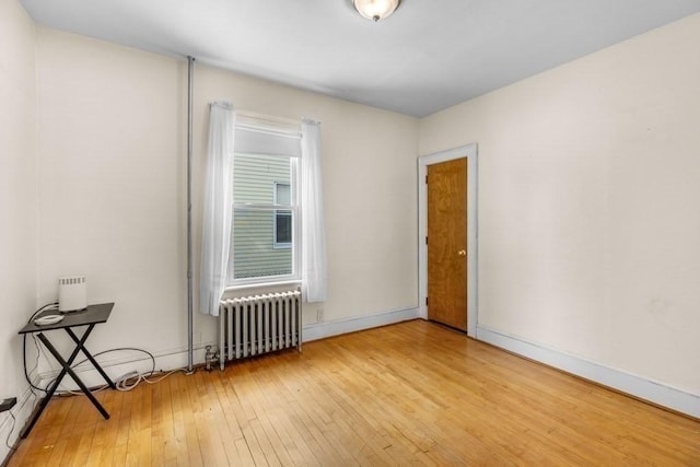 unfurnished room with radiator and light wood-type flooring