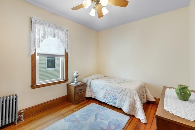 bedroom with ceiling fan, wood-type flooring, and radiator