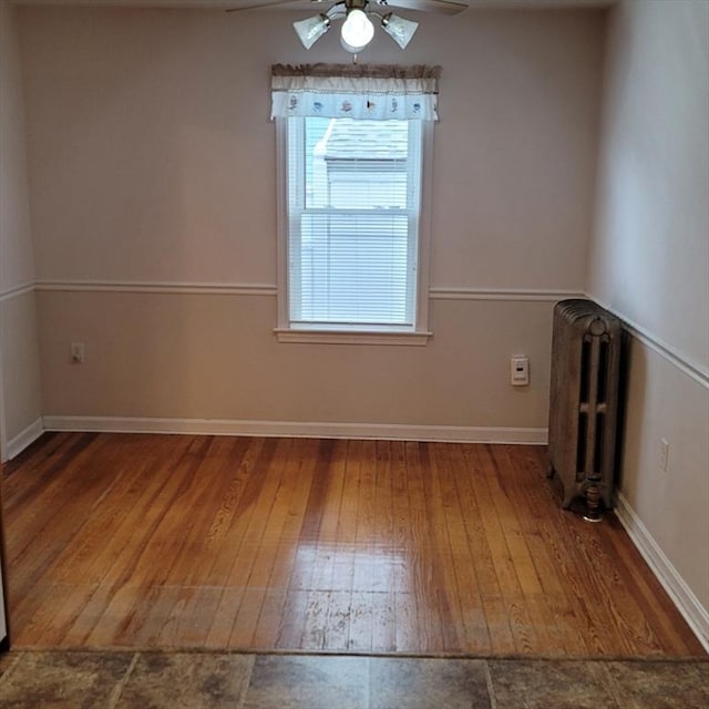 spare room with hardwood / wood-style floors, radiator, and ceiling fan