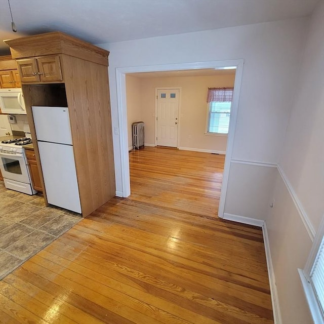 kitchen with white appliances, radiator heating unit, and light wood-type flooring