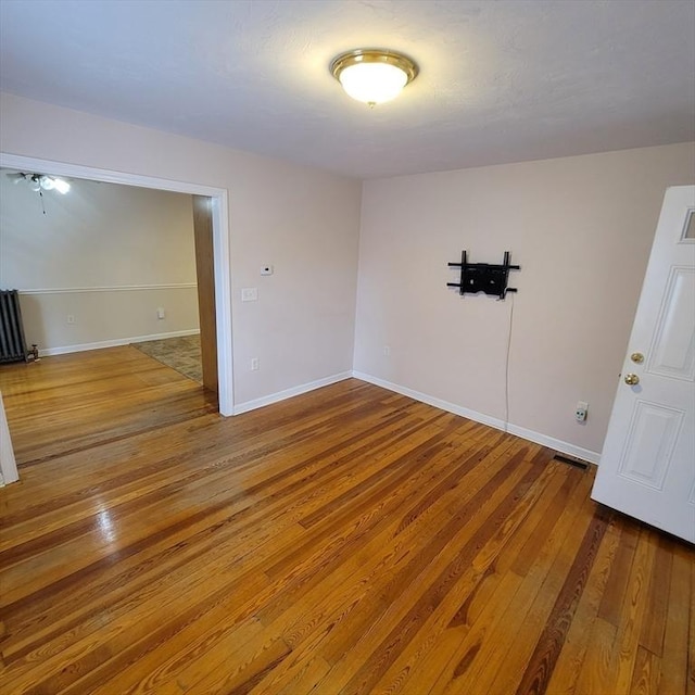 unfurnished room with wood-type flooring and radiator heating unit