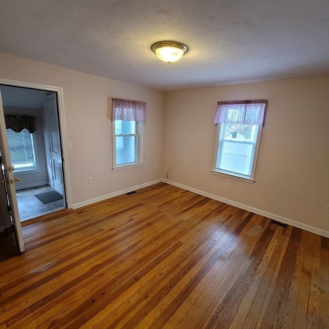 spare room featuring dark hardwood / wood-style floors and a healthy amount of sunlight