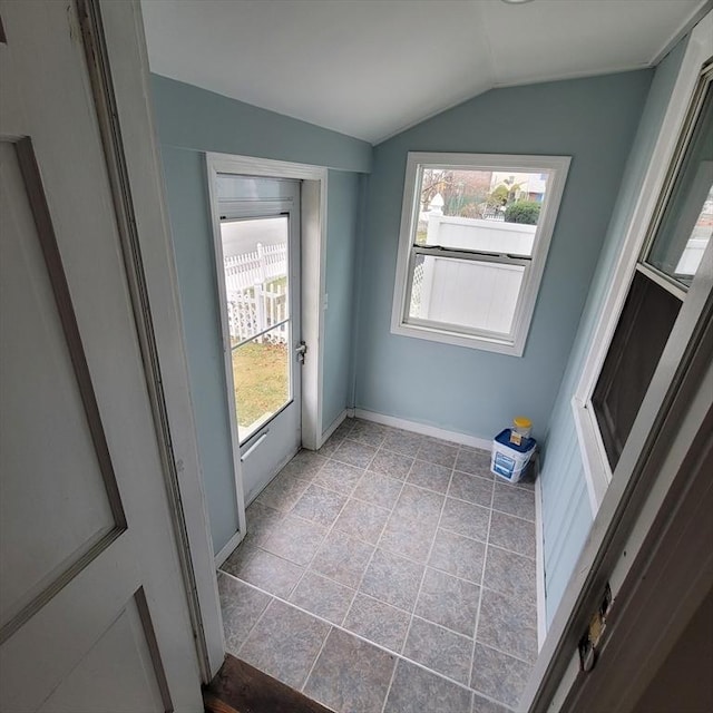 doorway featuring light tile patterned flooring and vaulted ceiling