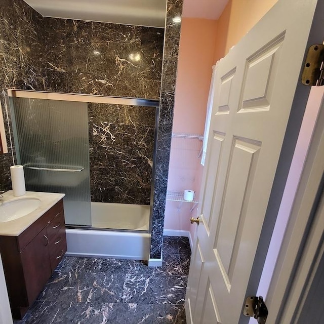 bathroom with vanity, combined bath / shower with glass door, and tile walls