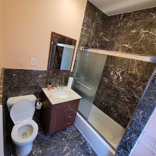 full bathroom with shower / bath combination with glass door, vanity, tile walls, and toilet