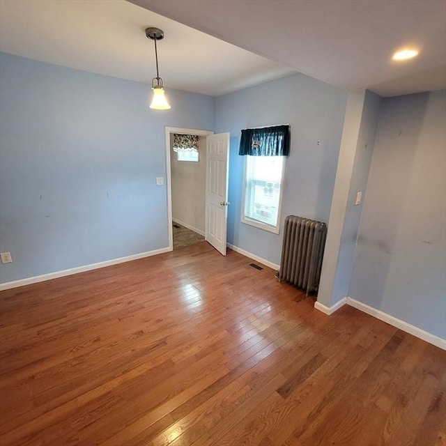 empty room with radiator heating unit and hardwood / wood-style floors