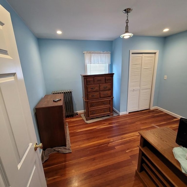 bedroom featuring a closet, radiator heating unit, and dark hardwood / wood-style floors