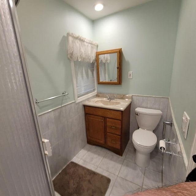 bathroom featuring tile patterned flooring, vanity, toilet, and tile walls