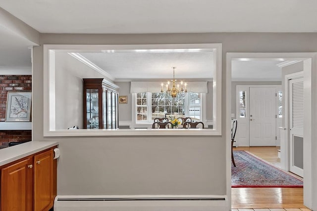 kitchen with a baseboard radiator, ornamental molding, light hardwood / wood-style flooring, and a notable chandelier