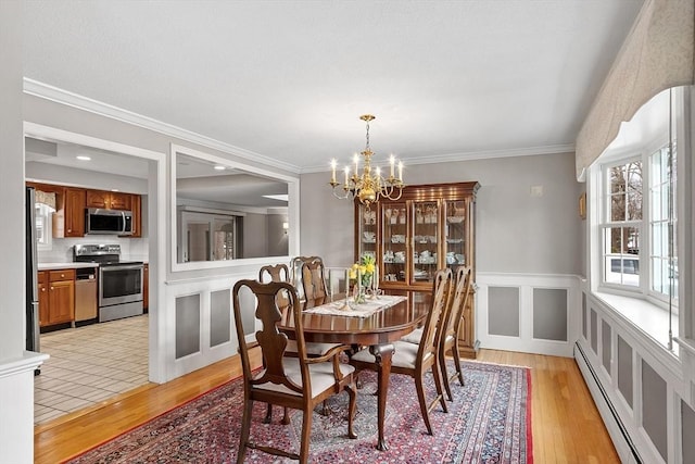 dining area with a baseboard radiator, ornamental molding, a chandelier, and light hardwood / wood-style floors