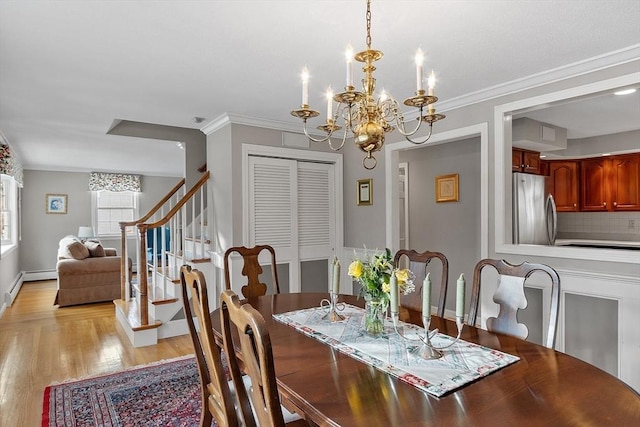 dining area with crown molding, an inviting chandelier, and light wood-type flooring