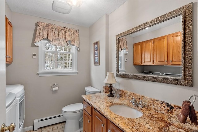 bathroom featuring baseboard heating, washing machine and clothes dryer, vanity, and toilet