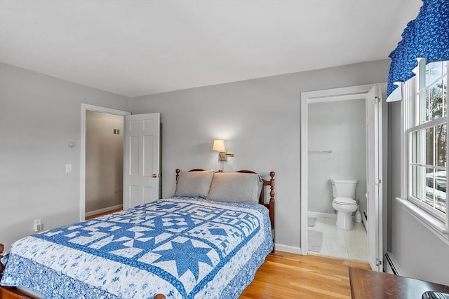 bedroom featuring baseboard heating, wood-type flooring, and ensuite bathroom