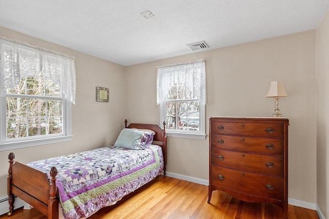 bedroom featuring a baseboard heating unit and light wood-type flooring