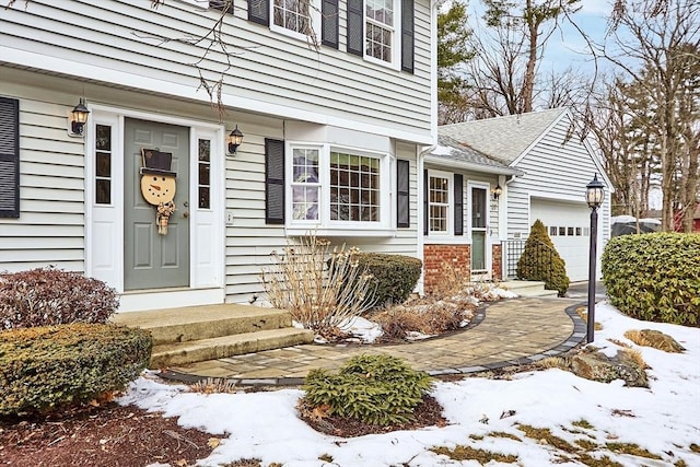 snow covered property entrance with a garage