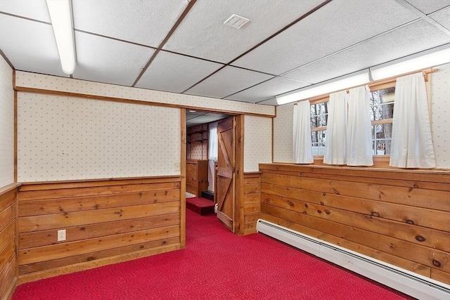 basement with a baseboard radiator, carpet, and wood walls