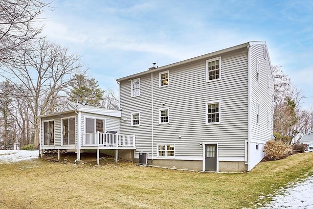 rear view of property with cooling unit, a sunroom, a wooden deck, and a lawn