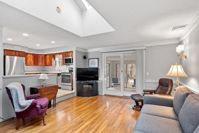 living room with a wealth of natural light, ornamental molding, and light wood-type flooring