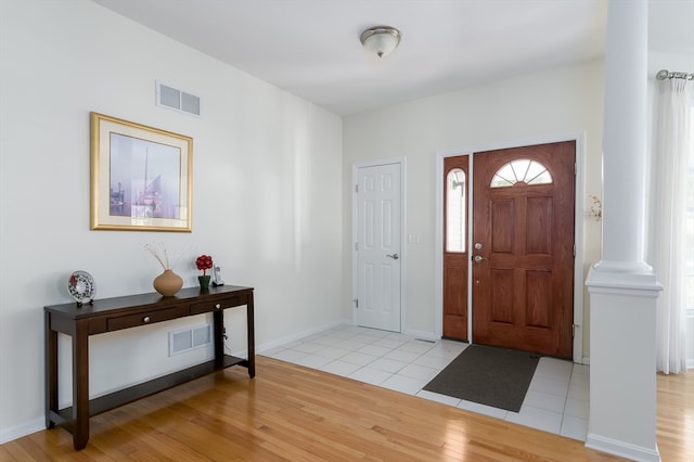 entryway featuring light wood-type flooring and decorative columns