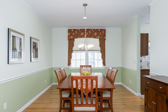 dining area with ornamental molding, a chandelier, and light hardwood / wood-style floors