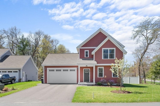 view of front of house featuring an attached garage, fence, a front lawn, and aphalt driveway