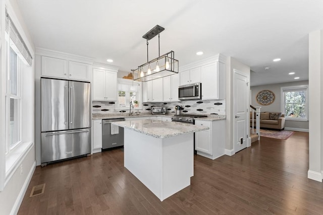 kitchen featuring baseboards, high end appliances, visible vents, and tasteful backsplash