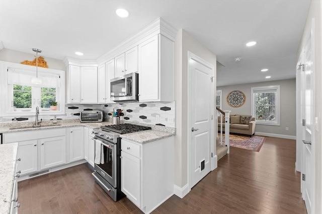 kitchen with visible vents, a sink, white cabinets, stainless steel appliances, and dark wood-type flooring