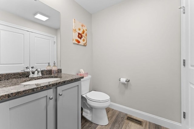 bathroom featuring visible vents, wood finished floors, baseboards, vanity, and toilet
