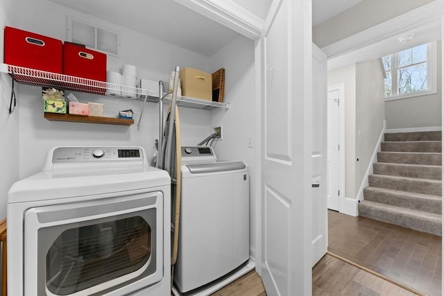 laundry room featuring laundry area, baseboards, washing machine and dryer, and wood finished floors