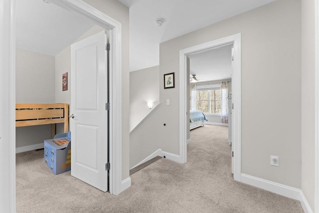 hallway with baseboards, carpet, and an upstairs landing
