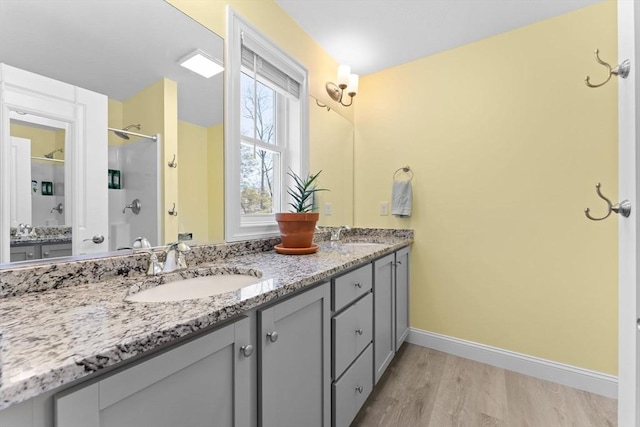 bathroom with a sink, baseboards, double vanity, and wood finished floors