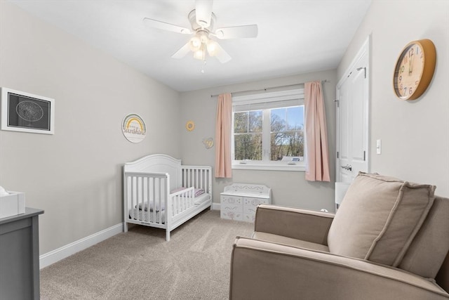 carpeted bedroom featuring baseboards, a crib, and ceiling fan