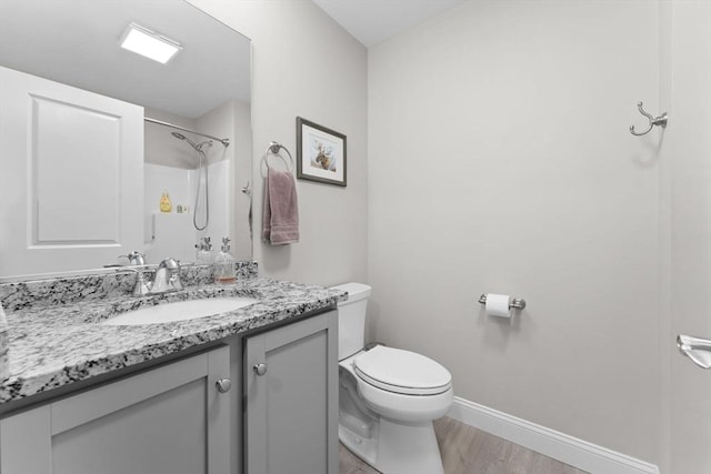 bathroom with baseboards, vanity, toilet, and wood finished floors