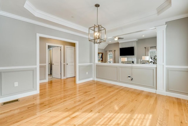 empty room featuring lofted ceiling, crown molding, hardwood / wood-style flooring, ceiling fan with notable chandelier, and ornate columns