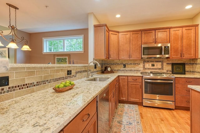44 Stevens Rd Unit 44, Hudson, MA 01749 - kitchen featuring appliances with stainless steel finishes, light wood finished floors, decorative backsplash, brown cabinets, and light stone countertops