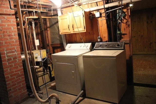 washroom with washer and dryer, cabinet space, and wooden walls