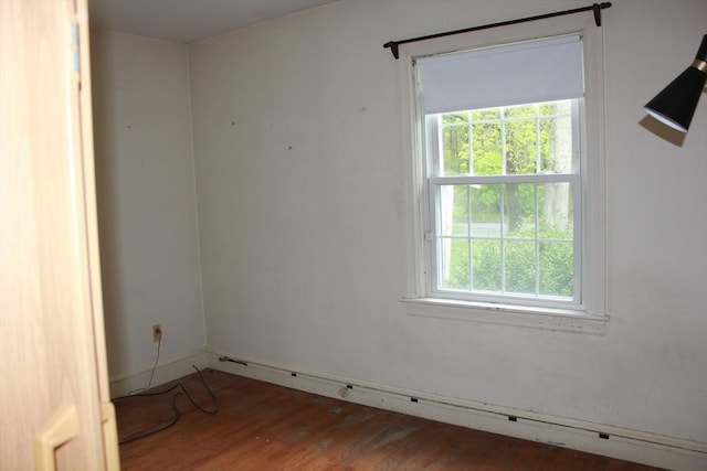 spare room featuring wood finished floors and a baseboard heating unit