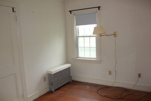 spare room with radiator, baseboards, and wood finished floors