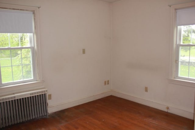unfurnished room with radiator, wood finished floors, and baseboards