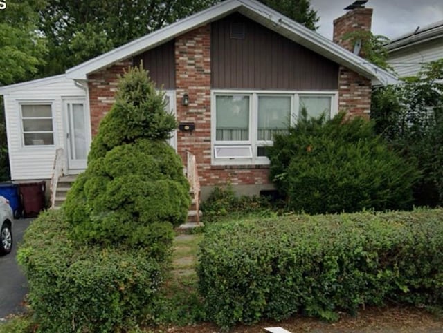 view of front of house featuring brick siding, a chimney, and entry steps