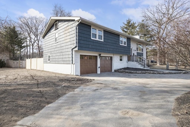 view of property exterior featuring driveway, a garage, and fence