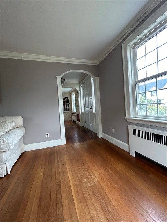 spare room featuring a healthy amount of sunlight, radiator, and hardwood / wood-style floors