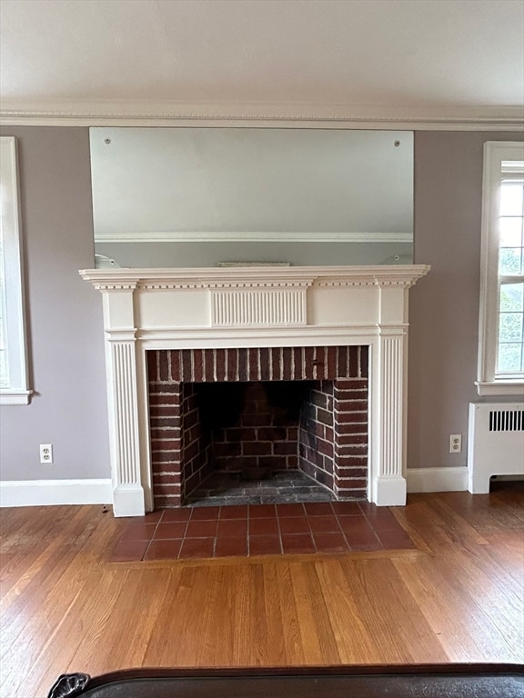 interior details featuring ornamental molding, radiator, hardwood / wood-style floors, and a brick fireplace